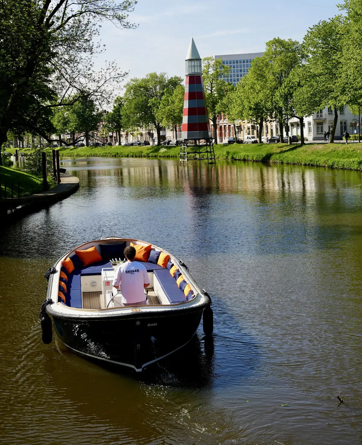 Ervaar Breda's open boat on the city canal, with the lighthouse in the background