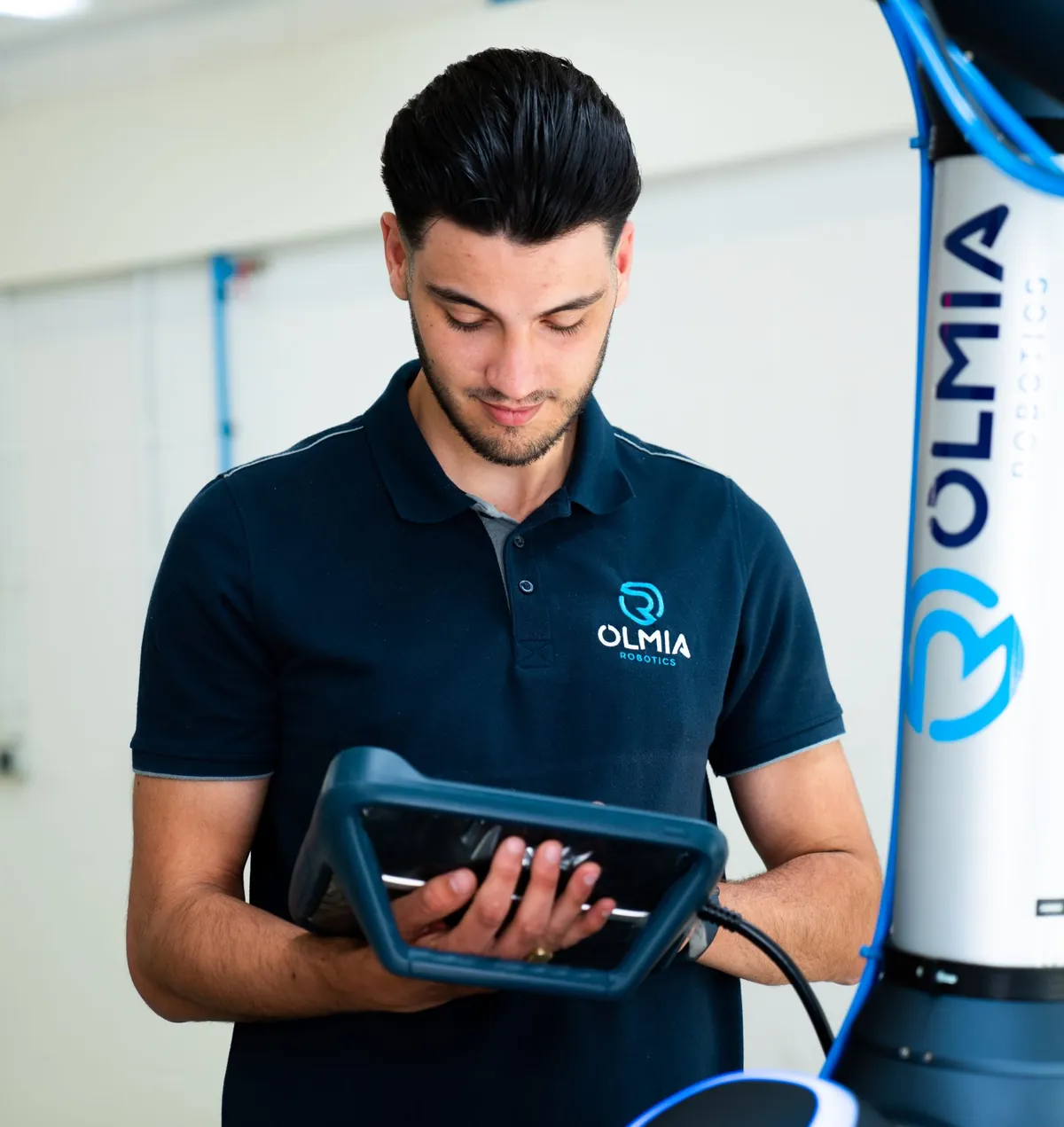 An Olmia Robotics employee programming a cobot