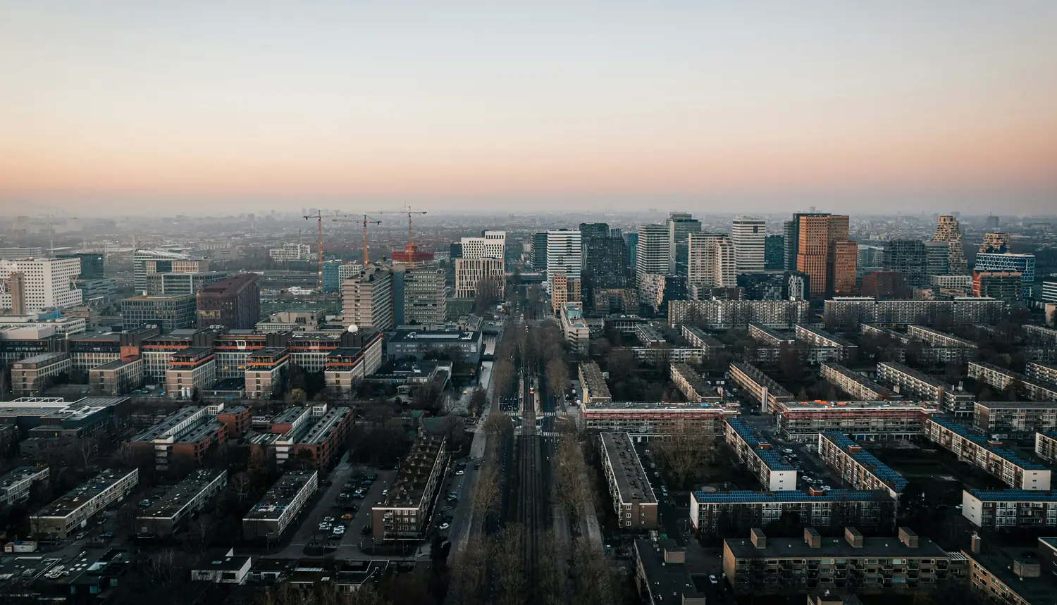 City skyline at dusk, with construction cranes between the buildings