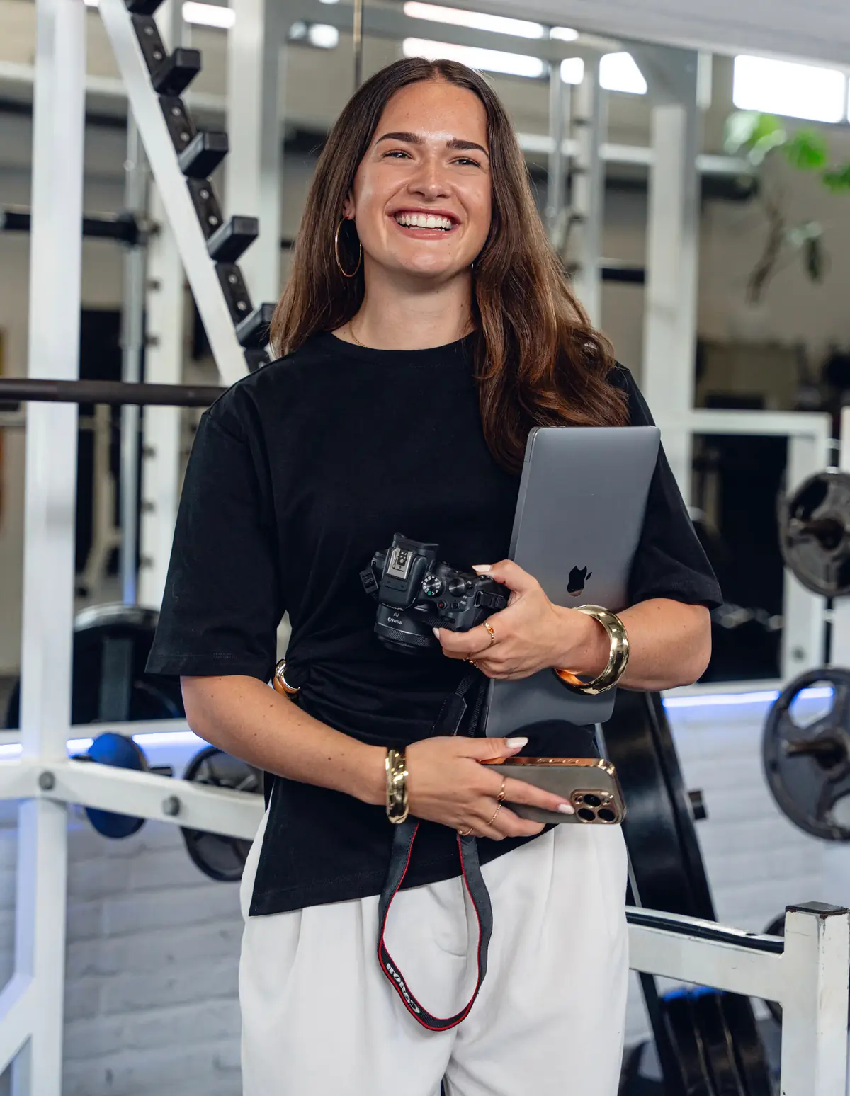 Karin from Social Fit with a camera and laptop in a gym