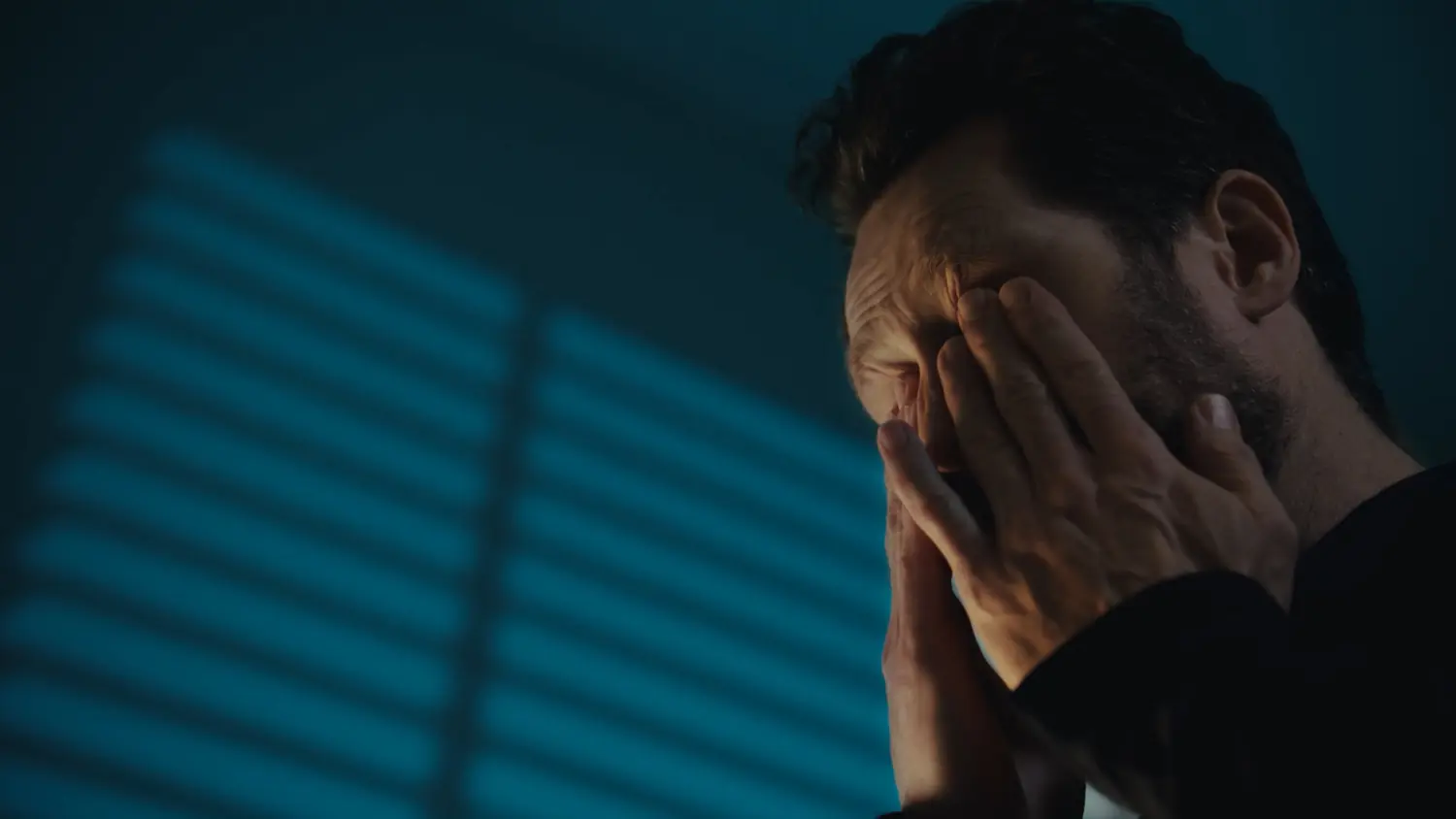 Still from a TH Motion video: a man rubbing his eyes in blue light
